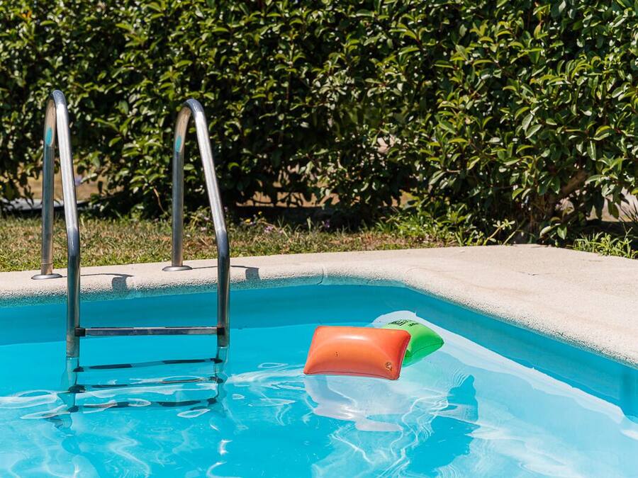A swimming pool with a metal ladder and a floating orange object.