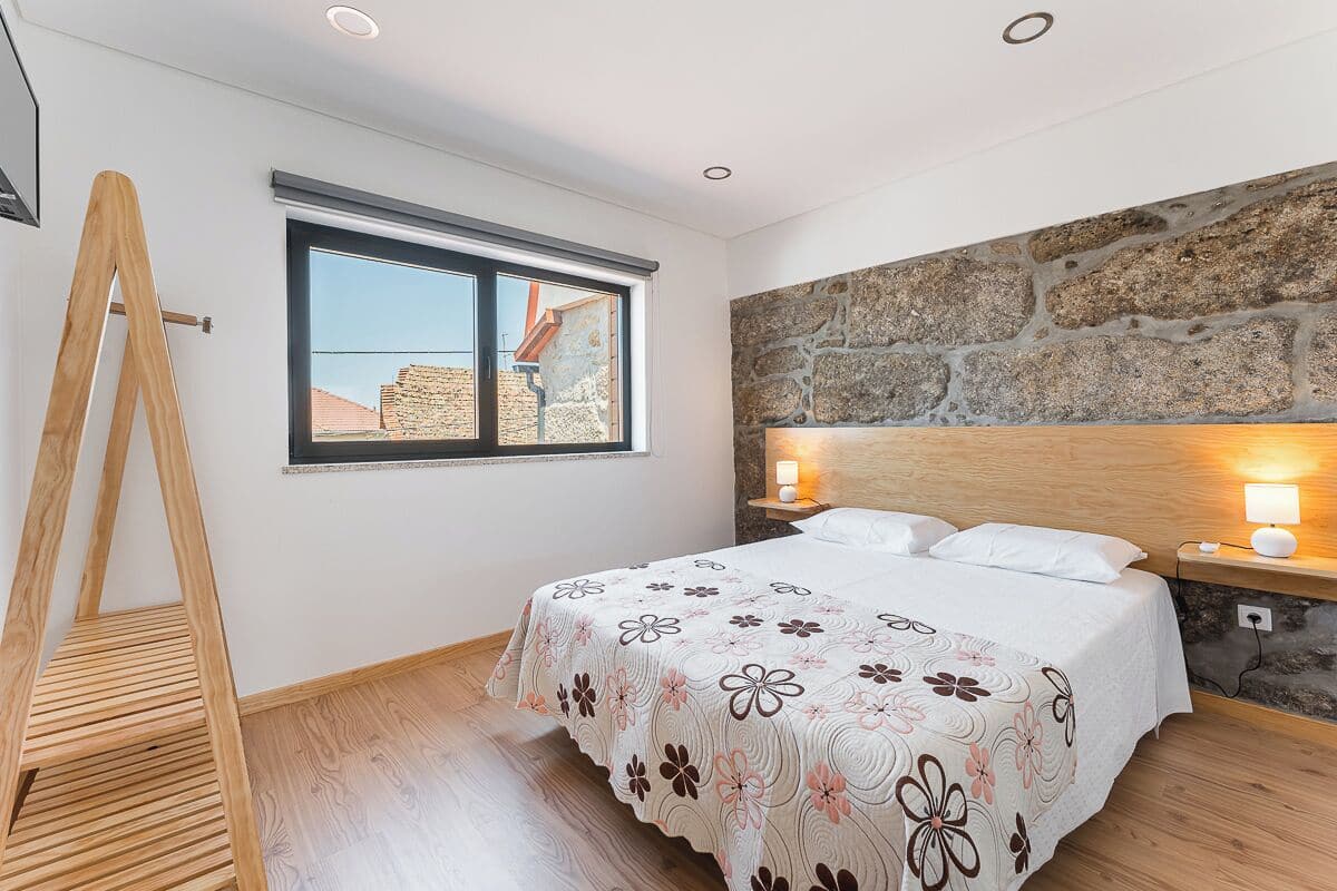 Une chambre à coucher avec un lit, une fenêtre, un mur en pierre et une échelle en bois.