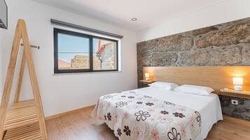 A bedroom with a bed, a window, a stone wall, and a wooden ladder.