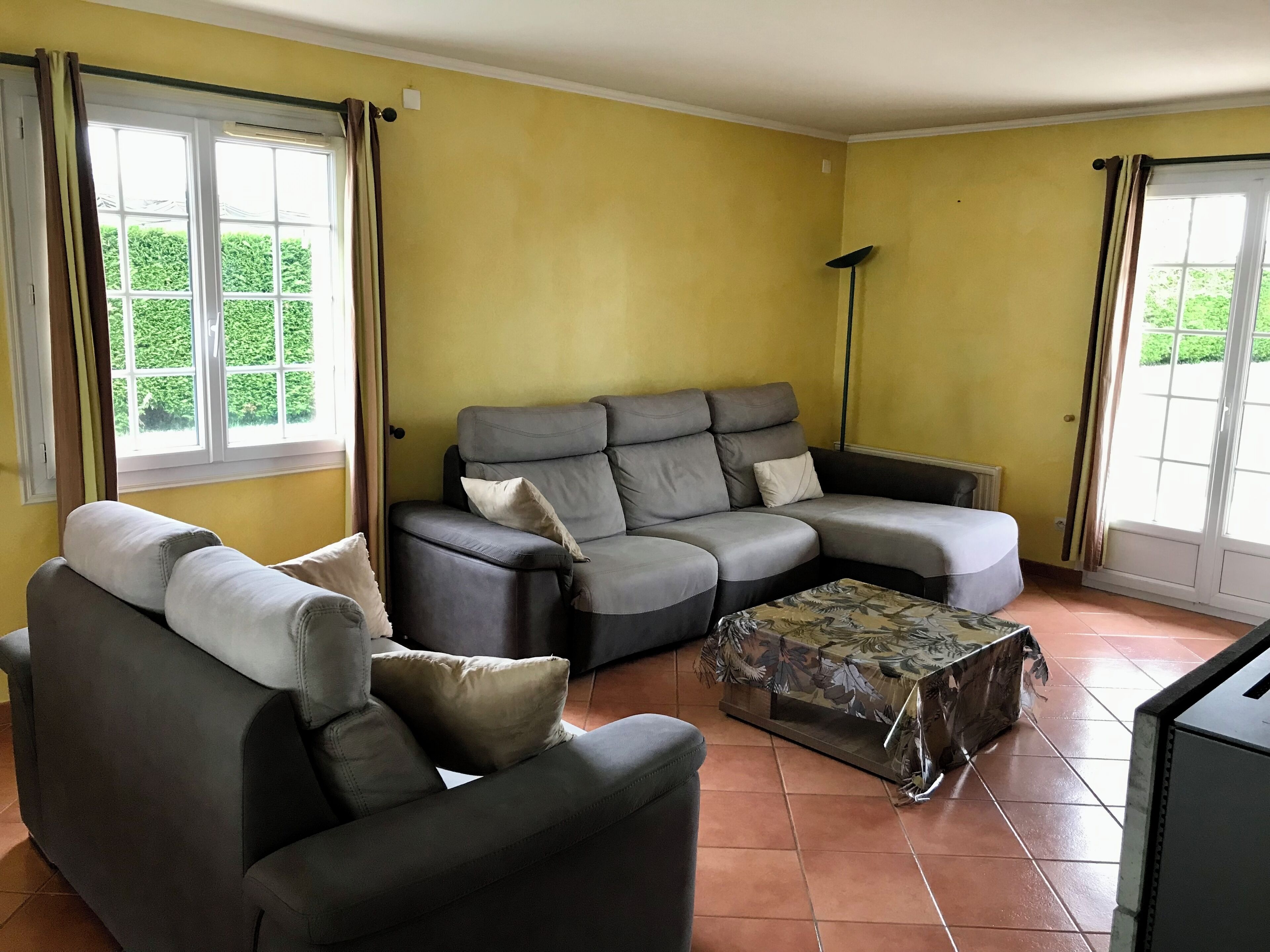A living room with a grey sectional sofa, a small table, and a floor lamp.