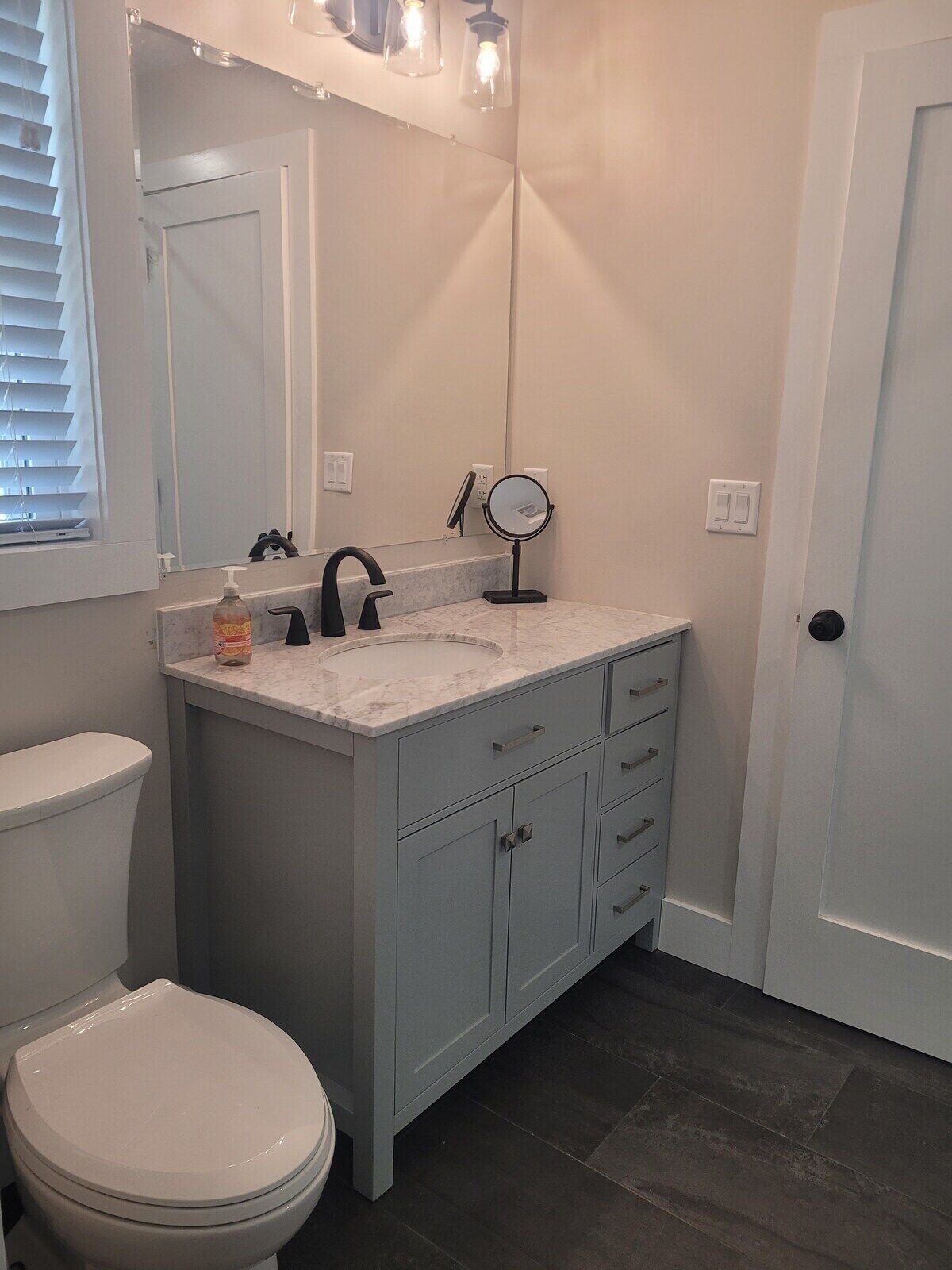 A bathroom with a toilet, a sink with a mirror, and a door.