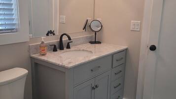 A bathroom with a toilet, a sink with a mirror, and a door.