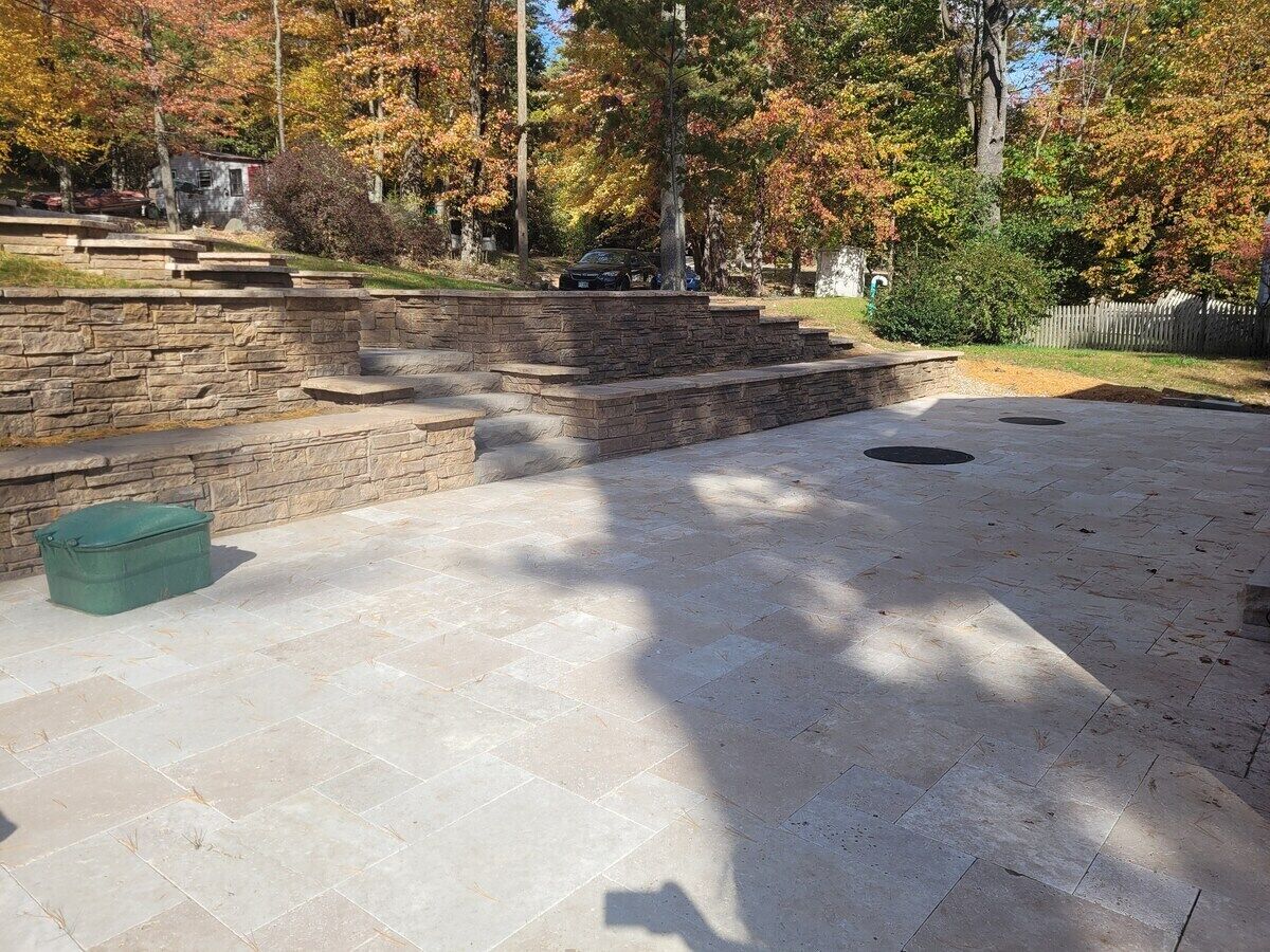A paved outdoor area with stone steps and a green container.