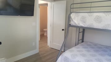 A room with a bunk bed, a television mounted on the wall, and a door leading to a bathroom.
