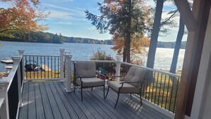 Una terraza de madera con dos sillas y vistas a un lago.