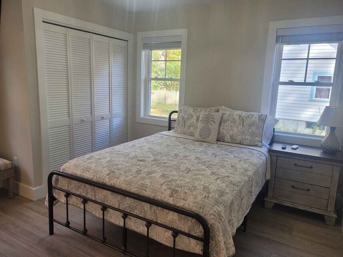 A bedroom with a bed, a nightstand, a window, and a closet.