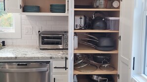 Una cocina con armarios blancos, horno empotrado y lavavajillas.
