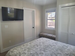 Un dormitorio con cama, televisión, ventana y armario.
