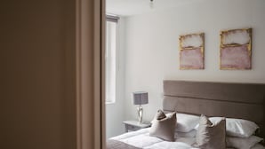 Ein Schlafzimmer mit einem Bett, Kissen, einem Nachttisch, einer Lampe und zwei Wandbildern.