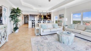 A spacious living room with a ceiling fan, a dining area, and a view of the city.