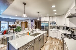 Une cuisine moderne avec des meubles blancs, des appareils électroménagers en acier inoxydable et un îlot central.