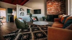 A spacious living room with a fireplace, a television mounted on the wall, and a modern sofa set. - Cardiff Hope House with Ocean View (Encinitas)