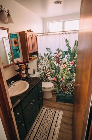 A bathroom with a sink, toilet, and shower curtain. - Cardiff Hope House with Ocean View (Encinitas)