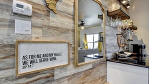 Et køkken med marmorbeklædt backsplash, et stort spejl og et skilt med teksten "AS FOR ME AND MY HOUSE WE WILL SERVE WINE".