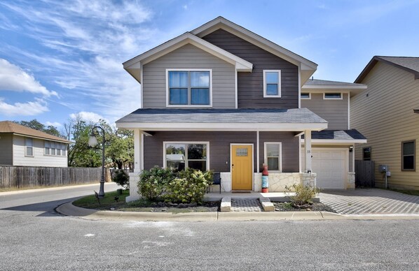 A two-story residential house with a front porch, a garage, and a well-maintained lawn.