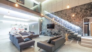A modern interior with a living area, sofa, and a staircase with a textured wall. - Luxury Villa Aurealis with Pool (Ližnjan)