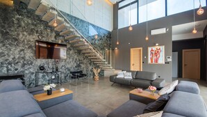 A modern living room with grey sofas, a stone wall, a staircase, and a flat-screen TV. - Luxury Villa Aurealis with Pool (Ližnjan)