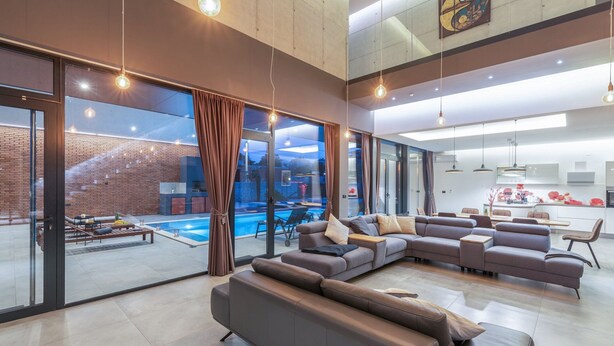A spacious living area with a large sectional sofa, a dining table, and a kitchen in the background. - Luxury Villa Aurealis with Pool (Ližnjan)