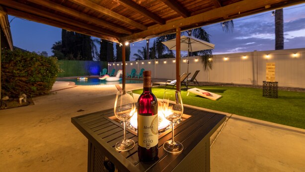 A patio area with a table, a bottle of wine, and two glasses. - Family 3BR POOL Home/ KING BED Suite/ BILLIARD TABLE/ Sleeps 9/near Yaamava' (Rialto)