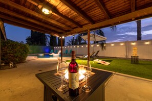 Eine Terrasse im Freien mit einem für zwei Personen gedeckten Tisch, inklusive einer Weinflasche und zwei Gläsern.