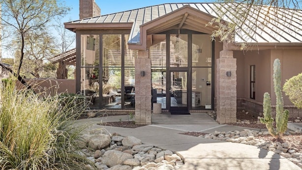 A modern house with a patio, large windows, and a stone facade. - Refreshing Desert Oasis: View, Sparkling Pool, Massage Chair, Remote Work Ready (Tucson)