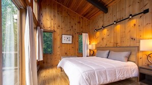 Un dormitorio de cabaña de madera con una cama grande, dos lámparas de noche y un cuadro en la pared.
