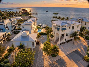 A coastal property with multiple buildings, a swimming pool, and a marina with boats.