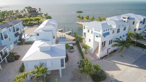 A coastal hotel with multiple buildings, a swimming pool, and a view of the sea. - Luxury Waterfront Estate—Pool, Spa, Game Lounge, 2 Docks & Ramp Access—Gulfside (Marathon)