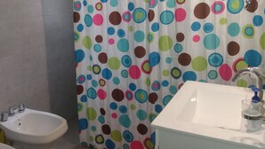 Een badkamer met een wit wastafel, een toiletbrons, een toilet en een douchegordijn met stippen.