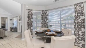 A dining area with a round table, four chairs, and patterned curtains. - Pet Friendly Paso Robles Wine Retreat (Templeton)