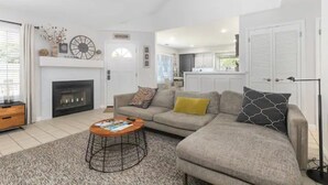 A modern living room with a fireplace, a sofa, a coffee table, and a kitchen in the background. - Pet Friendly Paso Robles Wine Retreat (Templeton)