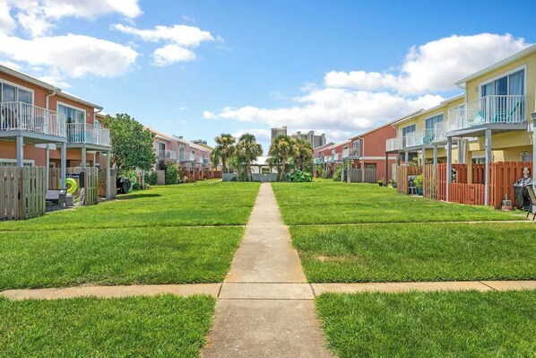 A row of townhouses with a central pathway, wooden fences, and a clear sky.