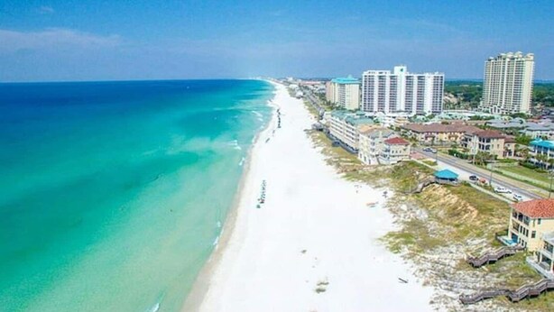 A coastal hotel with a beach view, multiple high-rise buildings, and a clear blue sky. - Location, location, location! Steps to the pool and just a 5-minute walk to the beach 🏖️💦 (Miramar Beach)
