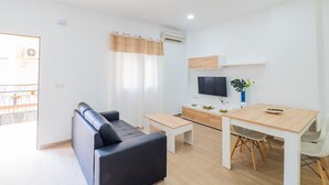 A modern living room with a sofa, a dining table, and a TV. - Cubo's Urban Studio Turisbelen / city / free wifi (Málaga)