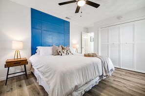 A bedroom with a large bed, a blue accent wall, a ceiling fan, and a white wardrobe. - Best Little Bunkhouse in TX! Walk to FIFA WORLD CUP (Arlington)