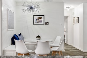A modern dining area with a round table, white chairs, and a unique ceiling light fixture. - Best Little Bunkhouse in TX! Walk to FIFA WORLD CUP (Arlington)