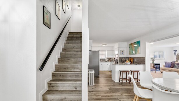 A modern kitchen with white cabinetry, a central island, and a dining area with white chairs. - Best Little Bunkhouse in TX! Walk to FIFA WORLD CUP (Arlington)
