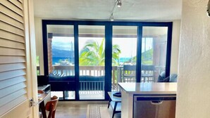 Eine moderne Küche mit einer großen Kochinsel, einem Essbereich mit Tisch und Stühlen und Meerblick durch große Fenster.