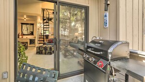 Un espace patio avec un barbecue, des portes-fenêtres coulissantes donnant sur le salon et un banc.