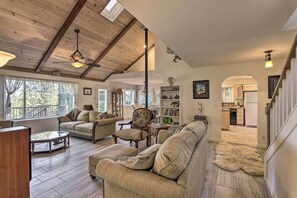 Amplia sala de estar con techo alto, vigas de madera y vista a la cocina a través de un arco.
