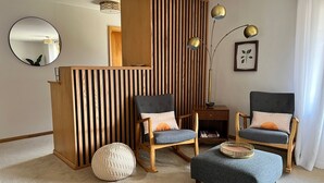 A living room with two armchairs, a round ottoman, a wooden partition, a mirror, and a floor lamp. - Beautifully styled, Mid Century Modern, family friendly Lake Mills House! (Lake Mills)