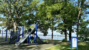 A playground with slides and climbing structures near a lake. - Beautifully styled, Mid Century Modern, family friendly Lake Mills House! (Lake Mills)