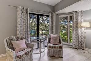 Relax in a serene space with two armchairs and a glass table, surrounded by a tranquil outdoor area.