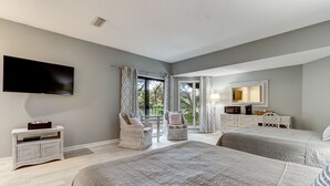 Een slaapkamer met twee bedden, een televisie, een dressoir en een stoel bij het raam.
