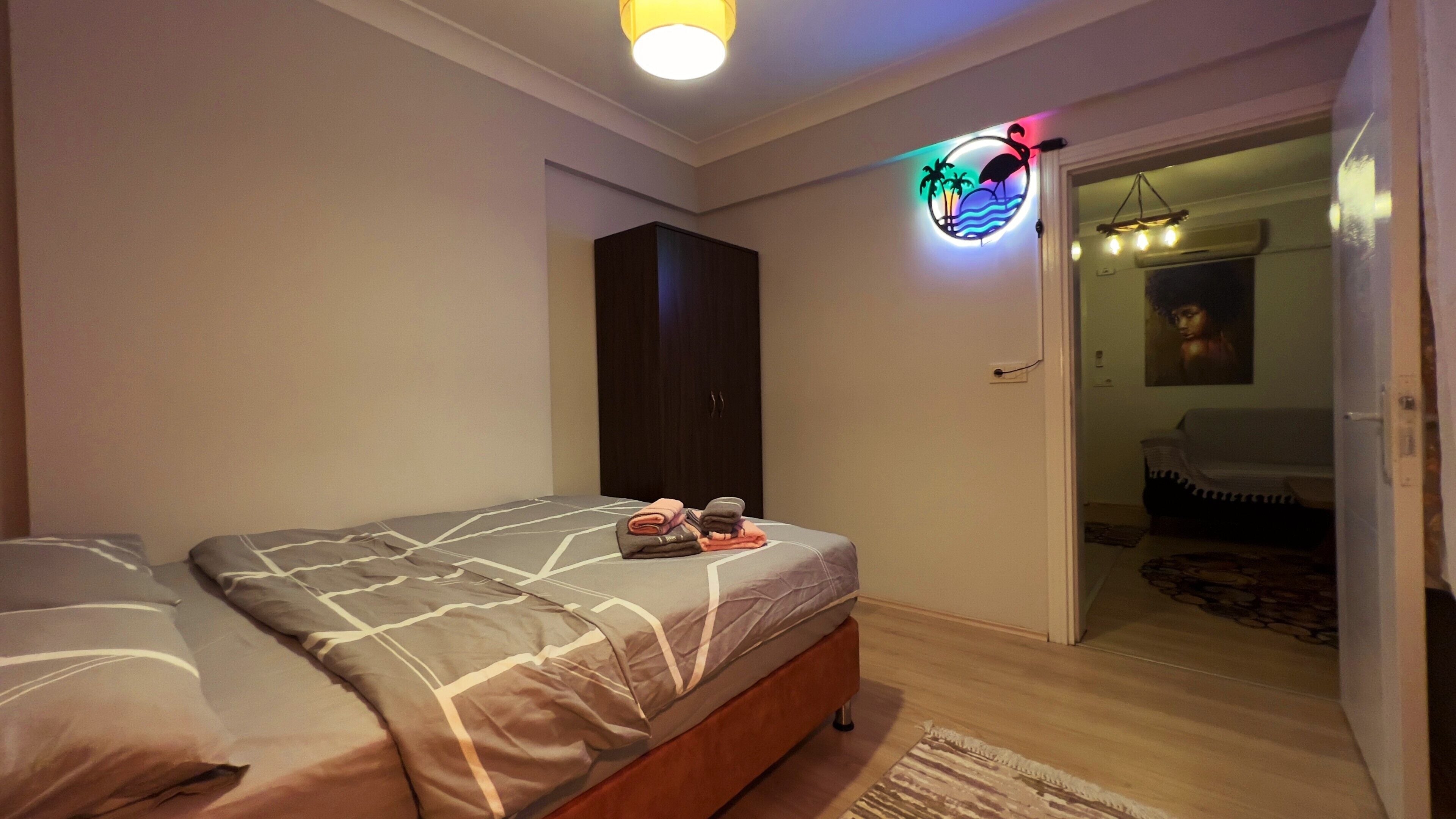 A bedroom with a bed, a wardrobe, and a door leading to another room.