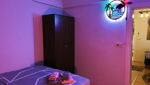 Um quarto com cama, guarda-roupa e luminária na parede.