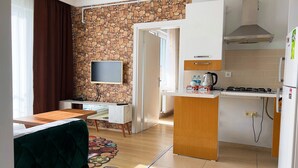 Cozinha compacta com parede de pedra, televisão de tela plana, pequena área de refeições e espaço de cozinha equipado.