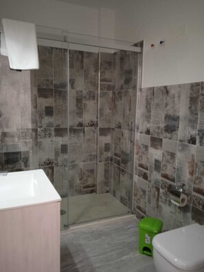 A bathroom with a shower, a toilet, and a sink. - Onyx Apartment (Avola)