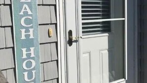 Une porte blanche avec un panneau en verre et une inscription qui dit : « BIENVENUE À LA MAISON DE PLAGE ».