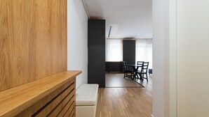 A modern interior with a wooden bench, a dining table with chairs, and a kitchen area in the background.